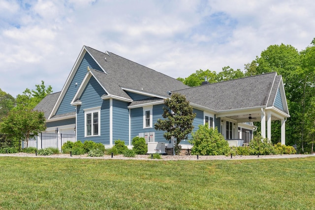 view of front of house featuring roof with shingles, fence, and a front yard
