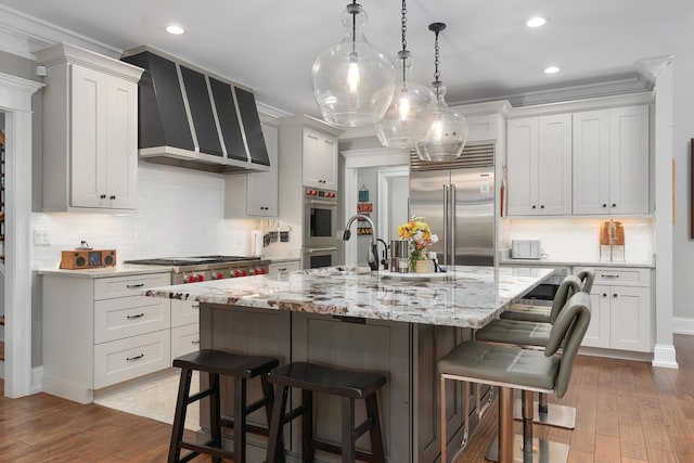 kitchen with ornamental molding, a breakfast bar area, recessed lighting, dark wood-type flooring, and stainless steel appliances