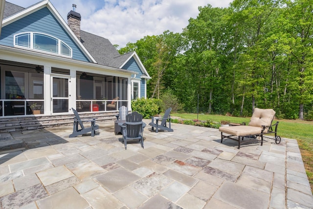 view of patio / terrace featuring ceiling fan, a sunroom, and an outdoor fire pit