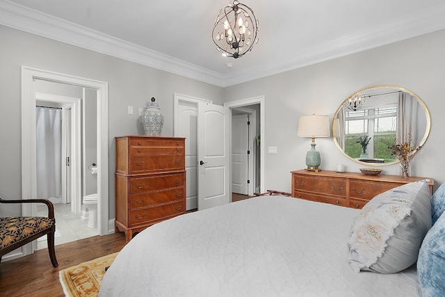 bedroom with ornamental molding, wood finished floors, ensuite bathroom, baseboards, and a chandelier