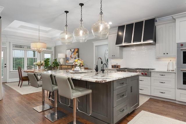 kitchen with crown molding, appliances with stainless steel finishes, a sink, a raised ceiling, and tasteful backsplash