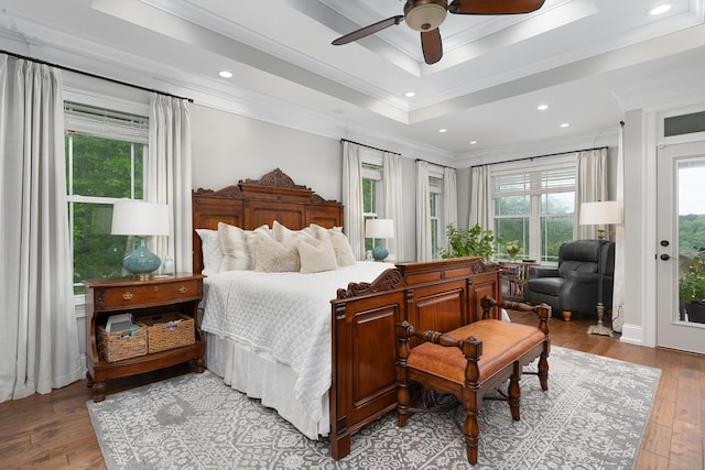 bedroom with crown molding, recessed lighting, a tray ceiling, and wood-type flooring