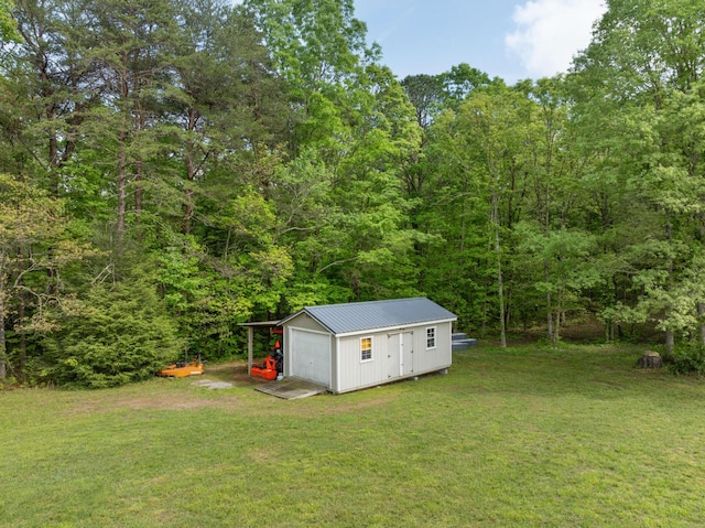 view of yard with a garage, an outbuilding, and a wooded view