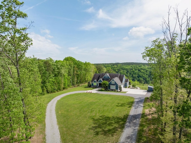 surrounding community featuring a yard, driveway, and a wooded view
