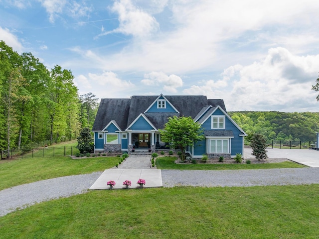 craftsman inspired home with a view of trees, fence, covered porch, and a front yard