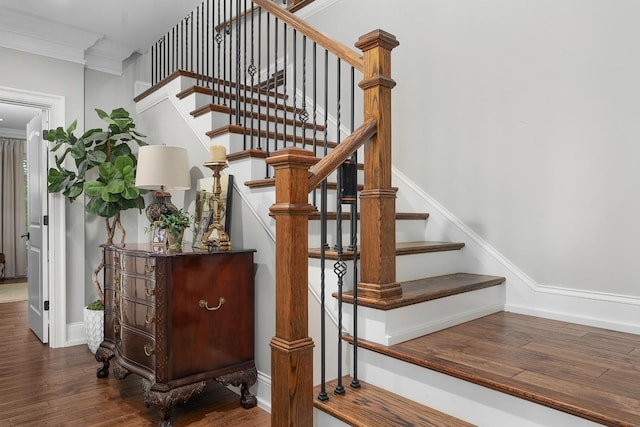 stairway with crown molding, baseboards, and wood finished floors