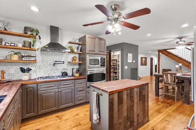 3124 Southall Rd, Franklin, TN 37064 - kitchen featuring butcher block counters, wall chimney exhaust hood, appliances with stainless steel finishes, open shelves, and ceiling fan