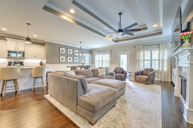 living area featuring ornamental molding, a decorative wall, and ceiling fan with notable chandelier