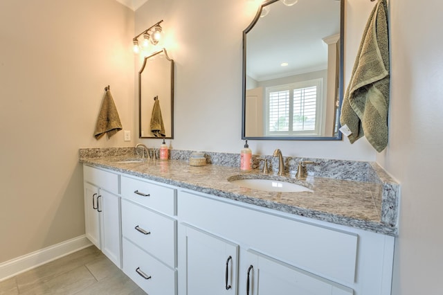 full bath featuring baseboards, crown molding, a sink, and double vanity
