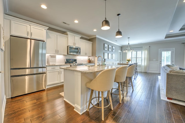 kitchen featuring visible vents, open floor plan, crown molding, white cabinets, and appliances with stainless steel finishes