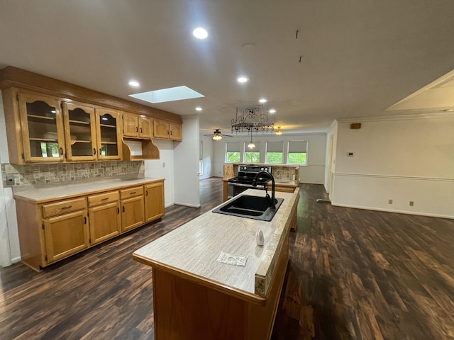 kitchen with decorative backsplash, stainless steel range with electric stovetop, glass insert cabinets, dark wood finished floors, and a skylight
