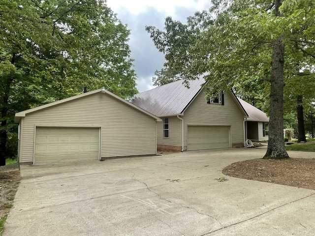 view of front of home featuring a garage, driveway, and metal roof
