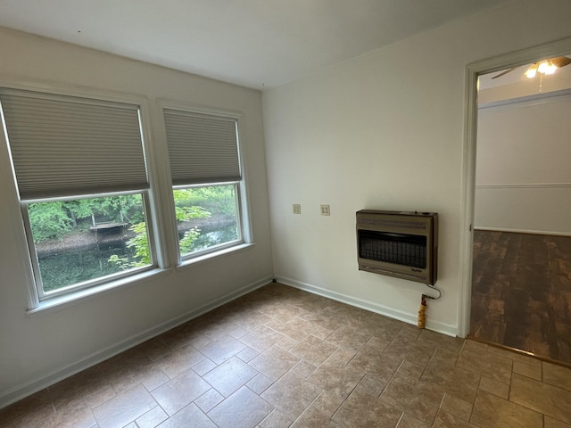 unfurnished living room with heating unit, baseboards, a ceiling fan, and stone finish flooring