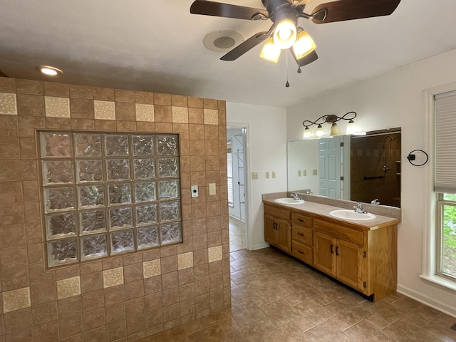 bathroom with ceiling fan, walk in shower, a sink, double vanity, and baseboards