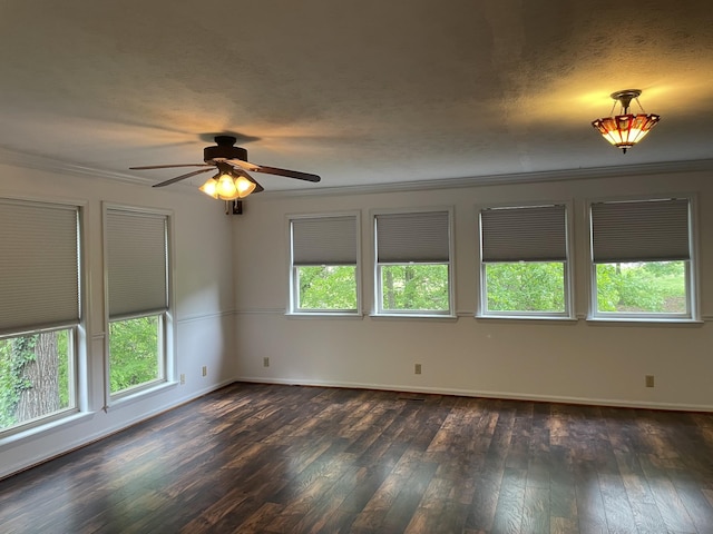 empty room with dark wood-type flooring, ornamental molding, a ceiling fan, and a healthy amount of sunlight