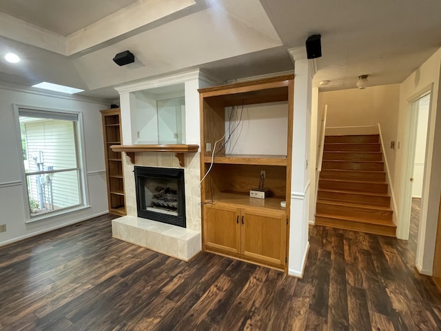 unfurnished living room featuring dark wood-type flooring, a raised ceiling, stairs, and a tile fireplace