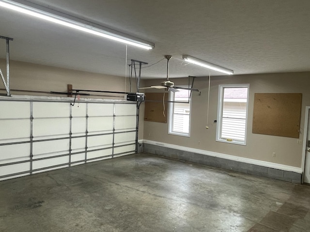 garage featuring a ceiling fan, baseboards, and a garage door opener