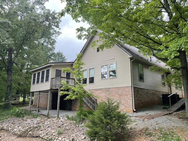 rear view of property featuring stairway, brick siding, a patio, and a deck