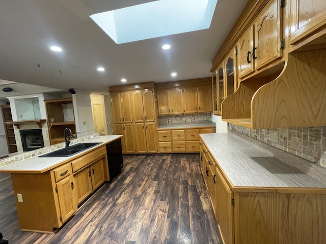kitchen with backsplash, a skylight, a fireplace, a sink, and black dishwasher
