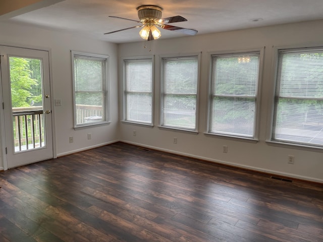 spare room with dark wood-type flooring, a ceiling fan, baseboards, and visible vents