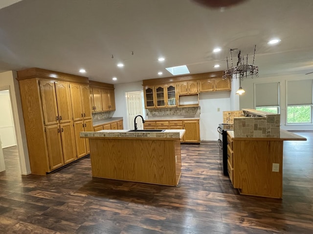 kitchen featuring decorative backsplash, a kitchen island with sink, dark wood finished floors, a sink, and recessed lighting