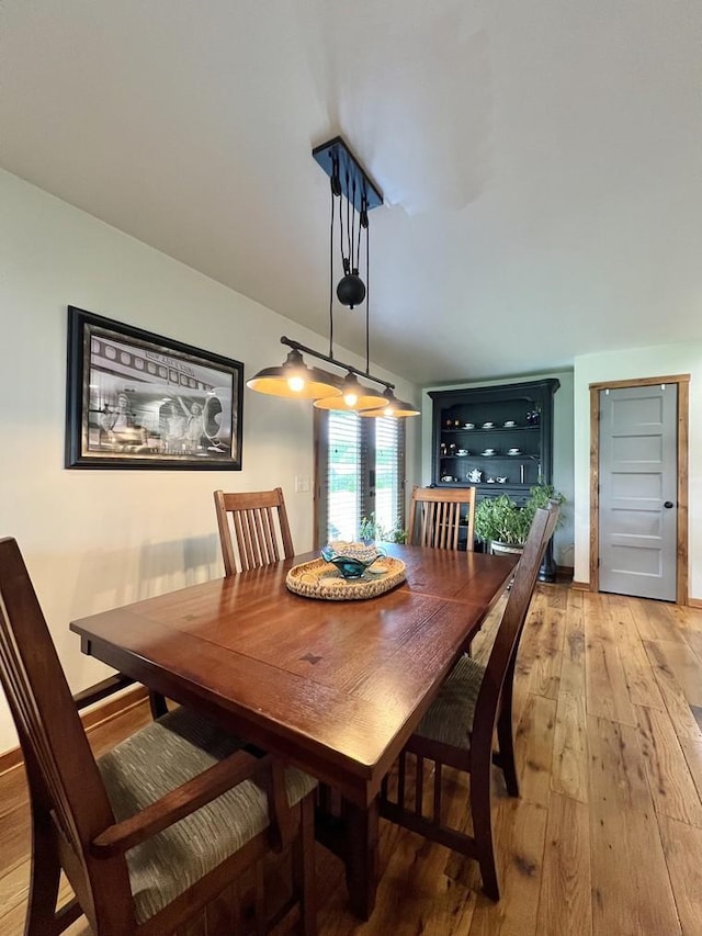 dining room featuring light wood finished floors and lofted ceiling