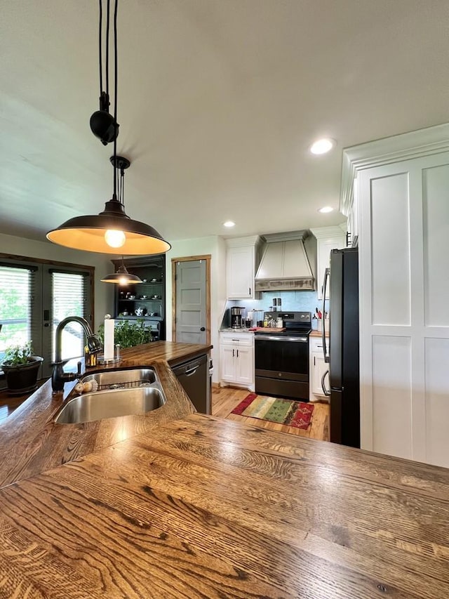 kitchen featuring freestanding refrigerator, premium range hood, electric range oven, a sink, and dishwasher