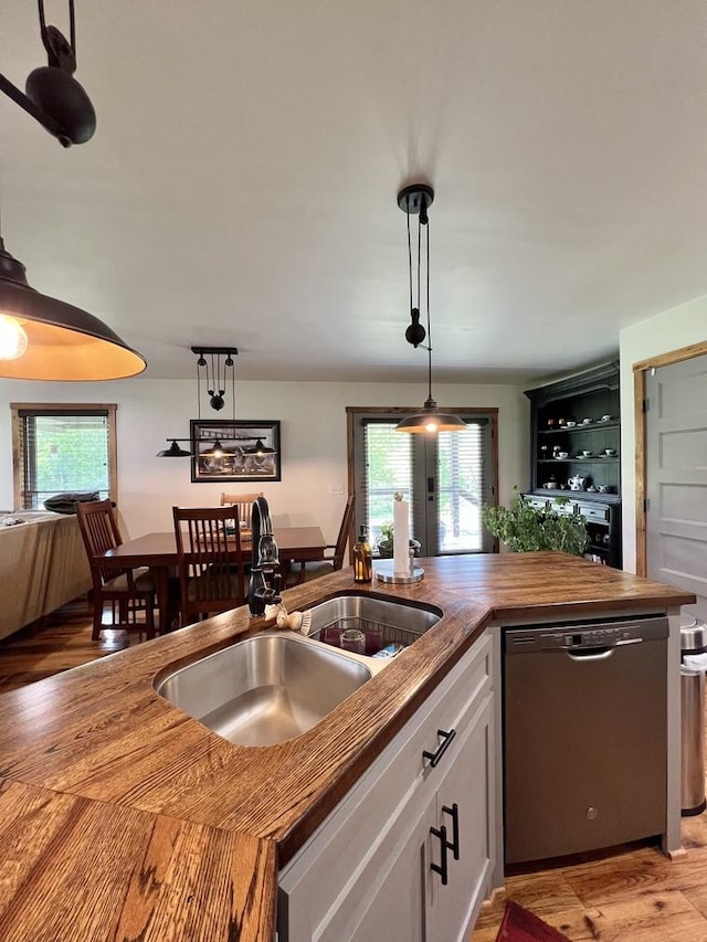 kitchen featuring a sink, dishwasher, white cabinetry, light wood-type flooring, and butcher block counters