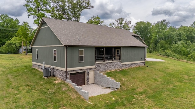 217 Rockhouse Rd, Hohenwald, TN 38462 - back of house featuring a lawn, an attached garage, a shingled roof, and stone siding