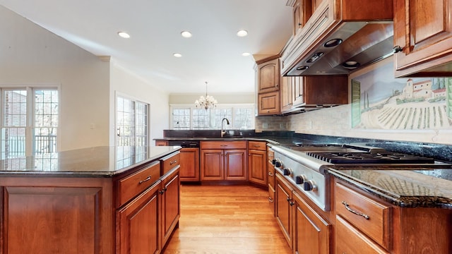 309 New Kent Ct, Tullahoma, TN 37388 - kitchen with stainless steel gas cooktop, brown cabinets, a sink, light wood finished floors, and under cabinet range hood