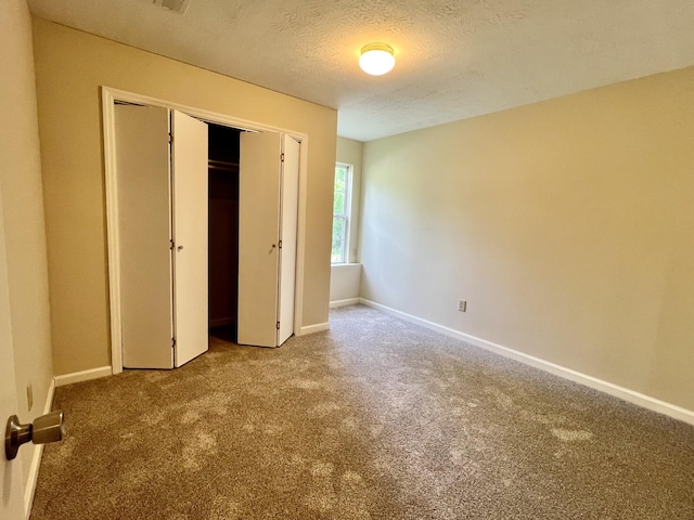 unfurnished bedroom with baseboards, carpet flooring, a textured ceiling, and a closet