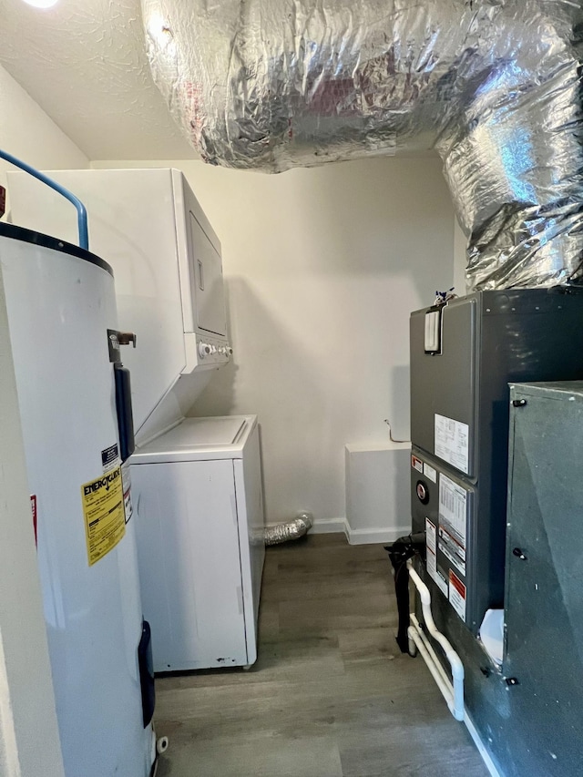 laundry area with laundry area, wood finished floors, stacked washer / dryer, baseboards, and electric water heater