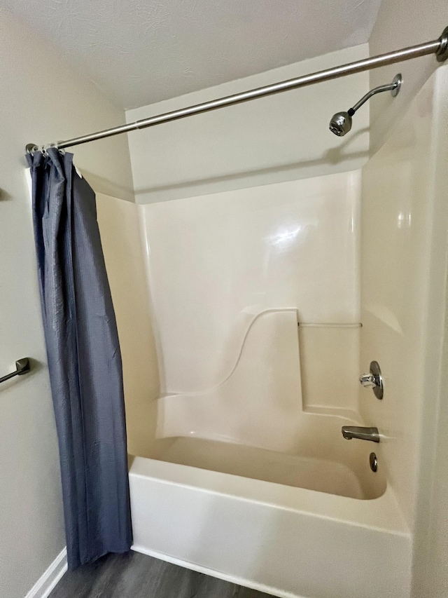 full bath featuring wood finished floors and shower / tub combo with curtain