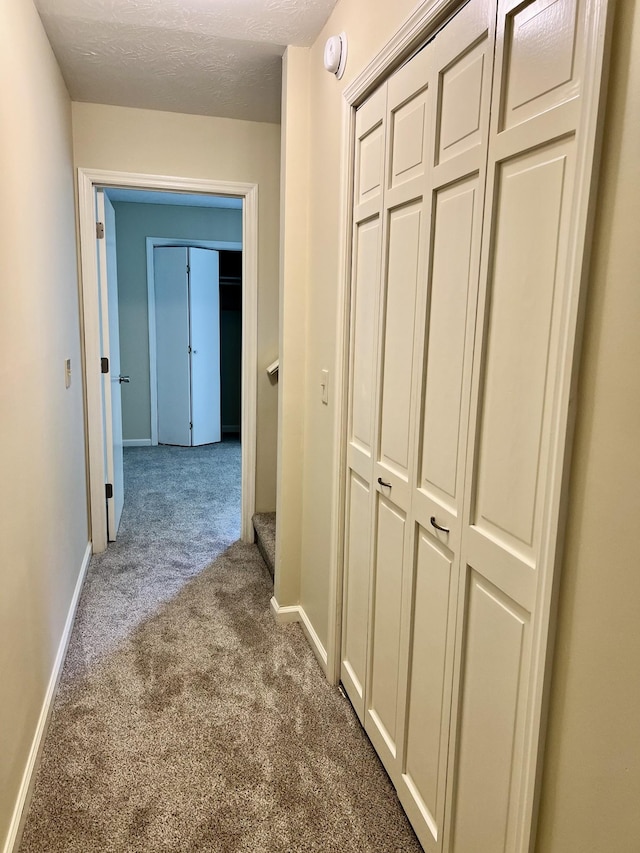 corridor with baseboards and carpet