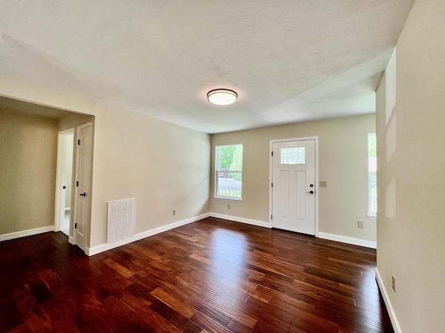 foyer entrance with baseboards, visible vents, and wood finished floors