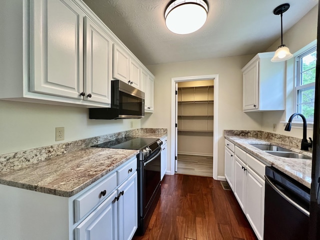 kitchen with dark wood finished floors, a sink, white cabinets, and black appliances