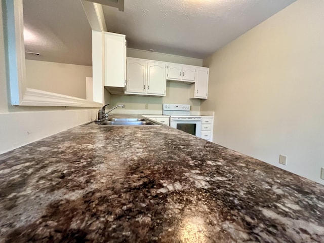 kitchen featuring a sink, white cabinets, white electric range, and a peninsula