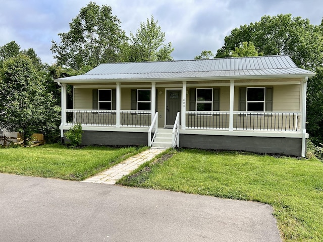 ranch-style home featuring covered porch, metal roof, and a front yard