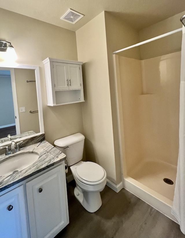 full bathroom featuring vanity, toilet, baseboards, a shower stall, and visible vents