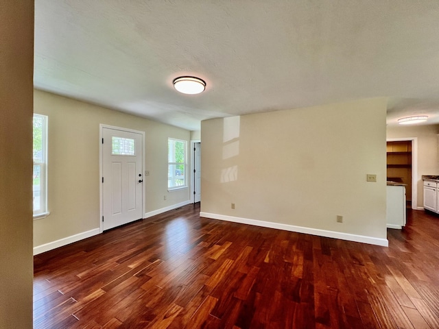 foyer entrance with baseboards and dark wood-style flooring