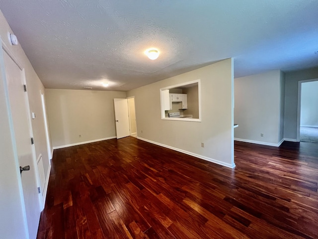 empty room with baseboards, a textured ceiling, and wood finished floors