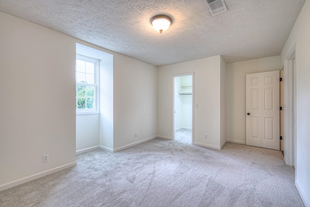 601 Foxborough Sq W, Brentwood, TN 37027 - unfurnished bedroom featuring light colored carpet, a textured ceiling, baseboards, and a walk in closet