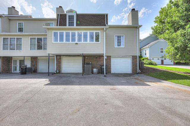 601 Foxborough Sq W, Brentwood, TN 37027 - back of house with driveway, a chimney, brick siding, cooling unit, and a garage