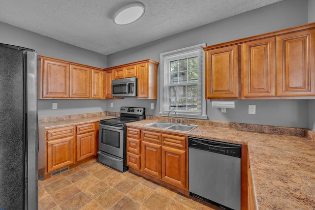 2408 Elliott Dr, Old Hickory, TN 37138 - kitchen featuring brown cabinetry, a textured ceiling, a sink, light countertops, and stainless steel appliances