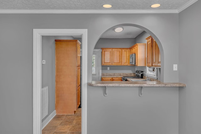 2408 Elliott Dr, Old Hickory, TN 37138 - kitchen with a breakfast bar, light countertops, arched walkways, a textured ceiling, and stainless steel appliances