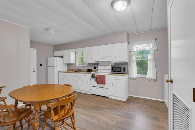 kitchen featuring white cabinets, white appliances, wood finished floors, under cabinet range hood, and visible vents