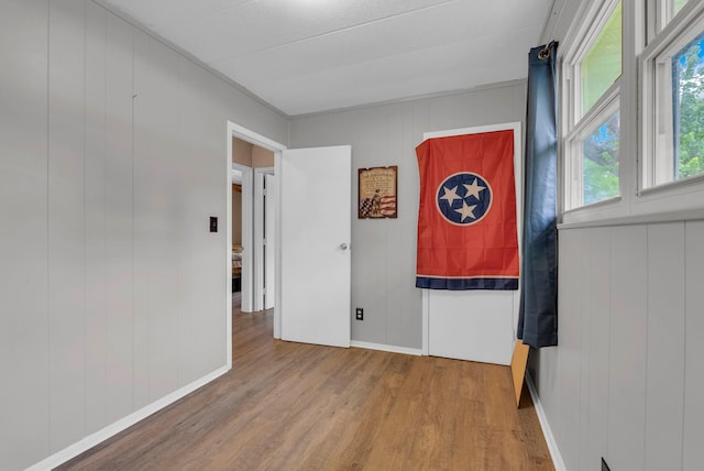 empty room featuring baseboards, a decorative wall, and wood finished floors