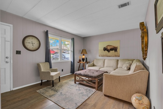 living area featuring baseboards, visible vents, and wood finished floors