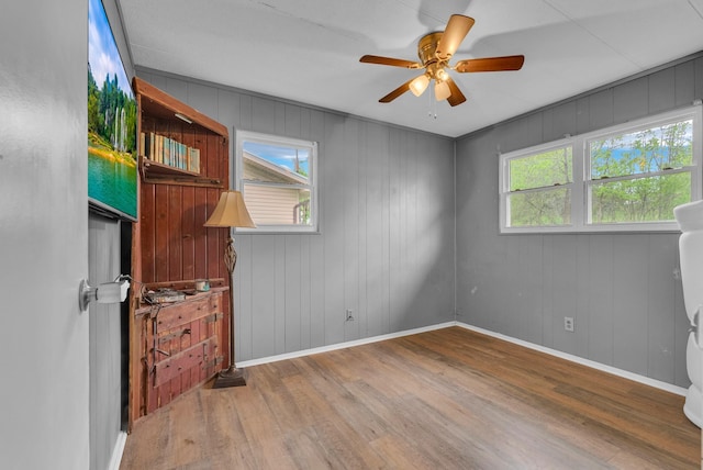 empty room with baseboards, ceiling fan, and wood finished floors