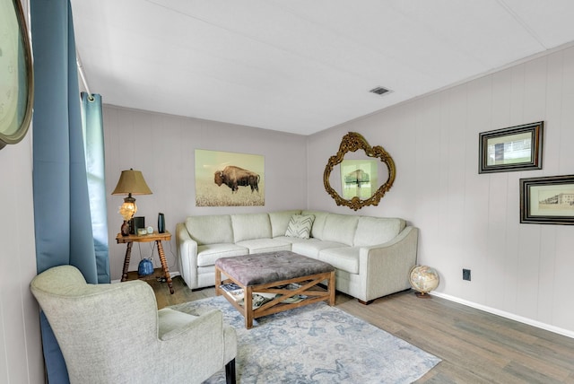 living area with baseboards, visible vents, and wood finished floors